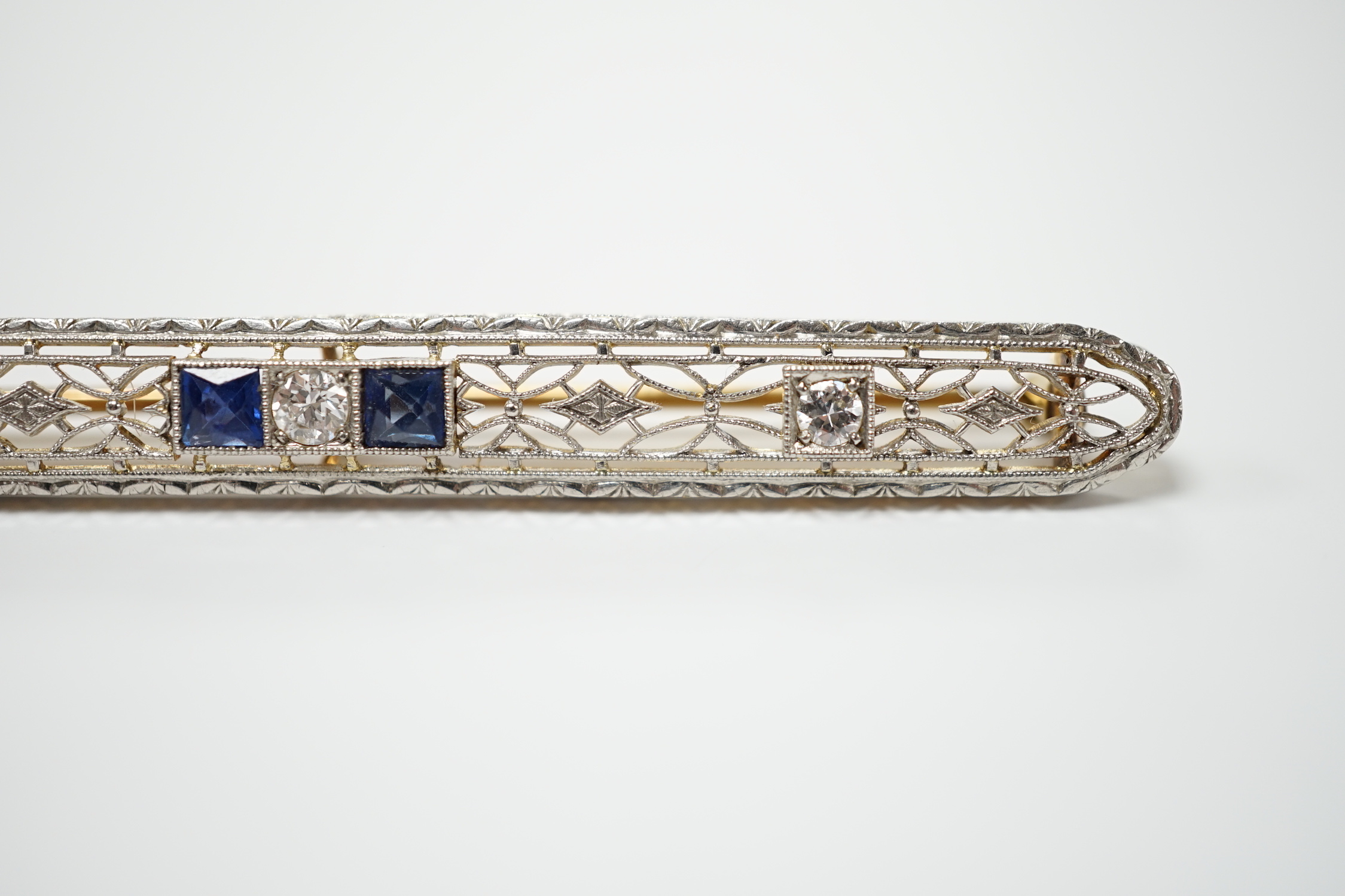 A Belle Époque style pierced 14k, sapphire and diamond cluster set bar brooch, 70mm, gross weight 5.5 grams.